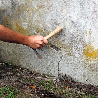 Bank forsiktig på pussen rundt sprekk i mur Bank forsiktig på pussen rundt sprekk i mur